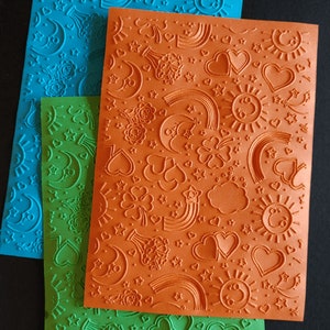 2x geprägtes Papier mit Kindermotiv, Sonne, Mond, Sterne, Wolken und Regenbögen. 17,8x12,7 cm - Art. -Nr. P-001