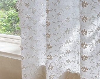 Könnte beinhalten: Weißer, durchsichtiger Vorhang mit einem zarten Blumenmuster. Die Blumen sind in hellbraun gestickt und in einem sich wiederholenden Muster angeordnet.