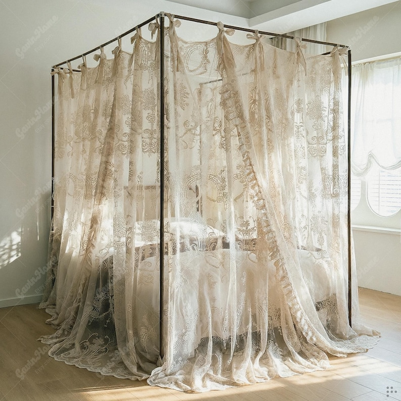 May include: A beige canopy bed with sheer, embroidered curtains. The curtains are draped around a dark metal frame, creating an elegant and airy aesthetic. The bed is made with matching bedding, creating a cohesive and inviting bedroom setting.
