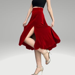 May include: A red velvet skirt with a high waist and a front slit. The skirt is flowing and has a slight flare. The model is wearing the skirt with a black top and silver heels.