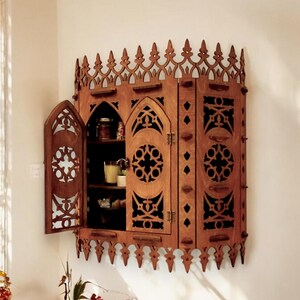 Peut inclure: Une armoire en bois avec un design gothique. L'armoire a une forme d'arche pointue et des sculptures complexes. Les portes sont ouvertes, r&eacute;v&eacute;lant des &eacute;tag&egrave;res &agrave; l'int&eacute;rieur.