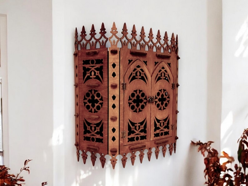 Peut inclure: Une armoire murale en bois de style gothique. L'armoire a deux portes avec des sculptures complexes et une arche en ogive. L'armoire est peinte en brun fonc&eacute;.