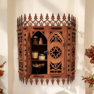 Peut inclure: Une armoire murale en bois avec un design gothique. L'armoire a deux portes avec des sculptures complexes et une &eacute;tag&egrave;re &agrave; l'int&eacute;rieur. L'armoire est peinte en brun fonc&eacute;.
