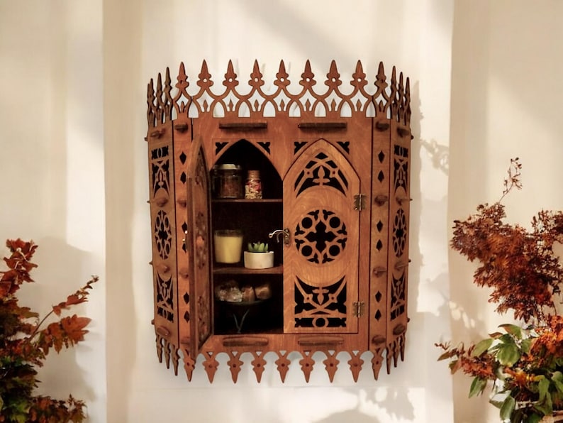 Peut inclure: Une armoire murale en bois avec un design gothique. L'armoire a deux portes avec des sculptures complexes et une &eacute;tag&egrave;re &agrave; l'int&eacute;rieur. L'armoire est peinte en brun fonc&eacute;.