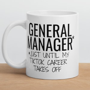 Può includere: Tazza da caffè in ceramica bianca con testo nero che recita "General Manager* *Just until my TikTok career takes off".