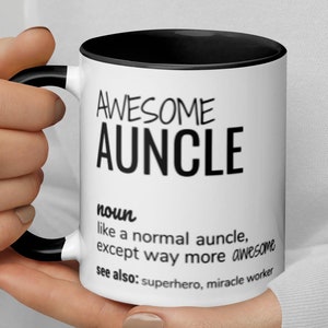 Può includere: Tazza da caffè bianca con bordo e manico neri. La tazza ha testo nero che recita "AWESOME AUNCLE noun like a normal auncle, except way more awesome see also: superhero, miracle worker"