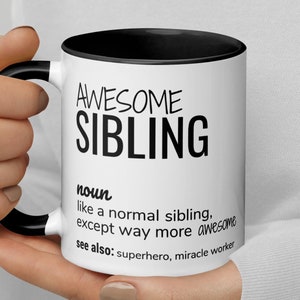 Op de afbeelding: Een witte keramische mok met een zwarte rand en handvat. De mok heeft zwarte tekst met de tekst "AWESOME SIBLING noun like a normal sibling, except way more awesome see also: superhero, miracle worker"