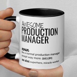 May include: White coffee mug with a black rim and handle. The mug has black text that reads "AWESOME PRODUCTION MANAGER noun like a normal production manager except way more awesome see also: superhero, miracle worker"