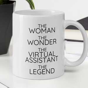 Könnte beinhalten: Eine weiße Keramik-Kaffeetasse mit schwarzem Text, der "The Woman The Wonder The Virtual Assistant The Legend" lautet.