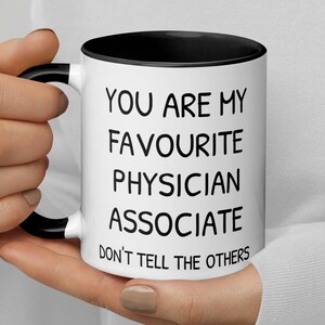 Könnte beinhalten: Eine weiße Kaffeetasse mit schwarzem Rand und Henkel. Die Tasse hat einen schwarzen Text mit der Aufschrift "You are my favourite physician associate don't tell the others."