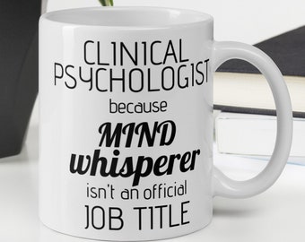 May include: White ceramic coffee mug with black text that reads "Clinical Psychologist because Mind Whisperer isn't an official job title."
