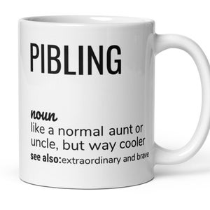 Può includere: Una tazza in ceramica bianca con una definizione in bianco e nero della parola "PIBLING" che è definita come "come una zia o uno zio normale, ma molto più cool." La definizione include anche "vedi anche: straordinario e coraggioso."