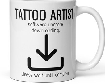 Könnte beinhalten: Eine weiße Keramik-Kaffeetasse mit schwarzem Text, der "Tattoo Artist software upgrade downloading..." lautet, und einem schwarzen Download-Symbol. Der Text unter dem Symbol lautet "please wait until complete."