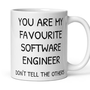 Könnte beinhalten: Weiße Keramiktasse mit schwarzem Text, der lautet: "Du bist mein Lieblings-Softwareentwickler. Verrate es nicht weiter."