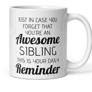 Op de afbeelding: Witte keramische koffiemok met zwarte tekst die luidt: "Just in case you forget that you're an Awesome Sibling This is your daily Reminder".