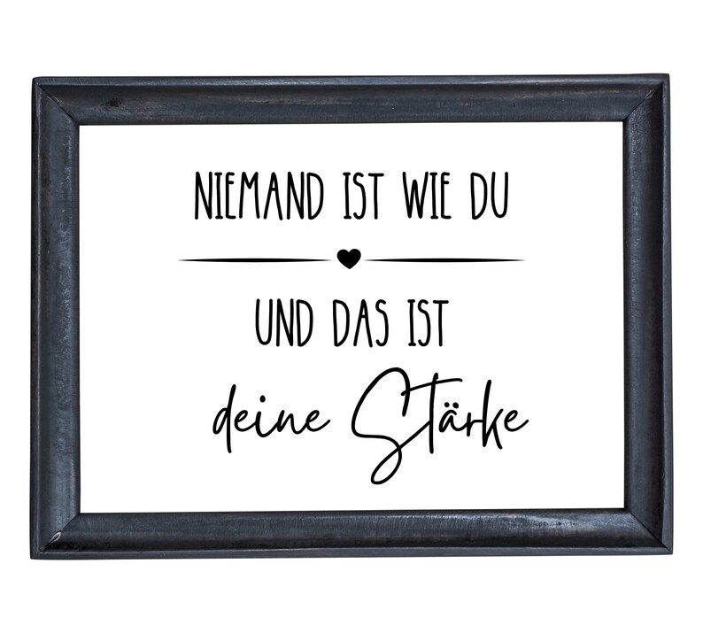 K&ouml;nnte beinhalten: Ein schwarzer gerahmter Druck mit wei&szlig;em Hintergrund und schwarzem Text, der "Niemand ist wie du und das ist deine St&auml;rke" lautet.
