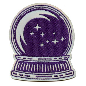 Pode incluir: Etiqueta bordada de ferro roxa de um globo de neve com uma lua crescente e estrelas dentro.