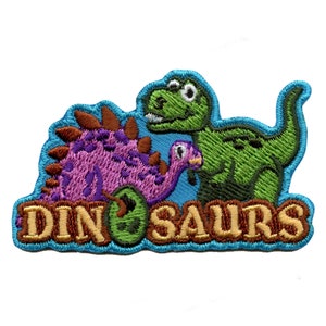 Puede incluir: Un parche bordado con un dinosaurio verde y un dinosaurio rosa sobre un fondo azul. El texto "DINOSAURS" está en letras marrones.