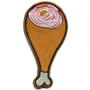 May include: An embroidered iron-on patch of a cartoon chicken leg. The leg is brown with a white bone and a pink and white swirl on top.