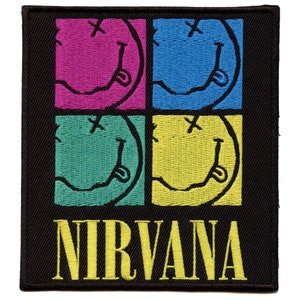 Peut inclure: Patch brodé noir avec quatre visages souriants colorés avec un 'X' pour les yeux et le mot 'NIRVANA' en lettres jaunes.