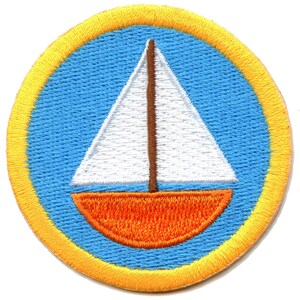 May include: Embroidered patch featuring a sailboat design. The patch has a blue background with a yellow border. The sailboat has a white sail and an orange hull. The mast is brown. This patch is suitable for jackets, bags, or other fabric items.