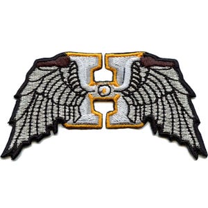 May include: White embroidered letter H with yellow outline and a small white circle in the center. The letter H is flanked by two gray and black embroidered wings.