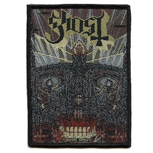 May include: A black and gold woven patch featuring the word "Ghost" in a gothic font. The patch depicts a dark, shadowy face with glowing red eyes and a mouth full of teeth. The text "©2015 GHOST" is visible at the bottom of the patch.