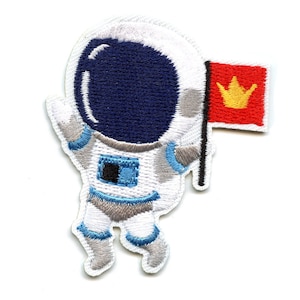 以下が含まれることがあります： 青いヘルメットをかぶった宇宙飛行士が黄色い王冠のついた赤い旗を持っている、白い刺繍のパッチ。