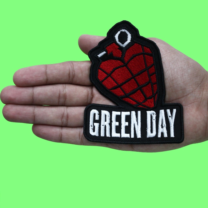 May include: A black and white embroidered patch with a red heart-shaped grenade and the text "GREEN DAY" in white.
