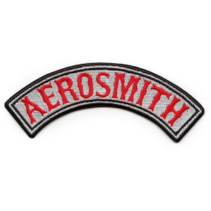 Könnte beinhalten: Ein gestickter grauer und schwarzer Aufnäher mit dem Wort "Aerosmith" in roten Buchstaben.