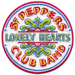 May include: Embroidered patch with the text "Sgt. Pepper's Lonely Hearts Club Band" in yellow and red lettering. The patch has a white background with a blue and red border, and a floral design in the center.