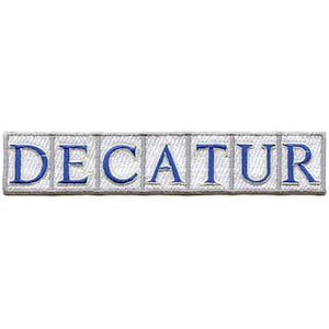 Puede incluir: Un parche bordado blanco con la palabra "DECATUR" en letras azules.