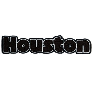 May include: Black felt patch with white outline spelling "Houston" in a bold, blocky font.