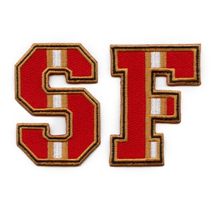 May include: Red and gold embroidered felt letters "SF" with white stripes.