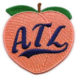 Puede incluir: Parche bordado en forma de melocotón con el texto "ATL" en letras cursivas azul marino.