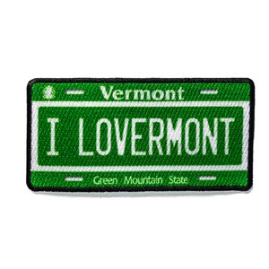 May include: Green and black embroidered patch with white text that reads "Vermont" and "I Love Vermont" with the words "Green Mountain State" below.