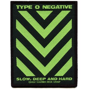 Op de afbeelding: Een rechthoekige patch met de tekst "TYPE O NEGATIVE" bovenaan en "SLOW, DEEP AND HARD" onderaan. De patch heeft een zwarte achtergrond met groene chevronstrepen. De onderkant van de patch luidt "©2022 WARNER MUSIC GROUP".