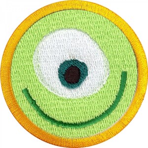 以下が含まれることがあります： 緑と黄色の刺繍パッチで、片目と笑顔の口があります。目は白で、緑と茶色の中心があります。