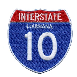 Puede incluir: Señal de carretera interestatal azul y roja con texto blanco. La señal dice "Interstate" y "Louisiana" y el número "10".