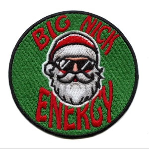 Op de afbeelding: Een ronde groene patch met een witte en rode kerstman met een zonnebril. De tekst "BIG NICK ENERGY" staat in rood rond de kerstman.