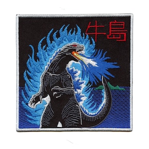 May include: An embroidered patch featuring a black Godzilla-like monster with blue flames, breathing fire, against a black background. The Japanese text "牛鬼" is in red above the monster.