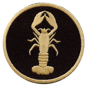 May include: A gold embroidered patch with a black background featuring a lobster design.