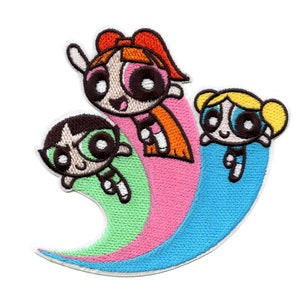 May include: An embroidered patch featuring the Powerpuff Girls, Blossom, Bubbles, and Buttercup, flying on a rainbow-coloured trail. The patch is white with pink, blue, and green accents.