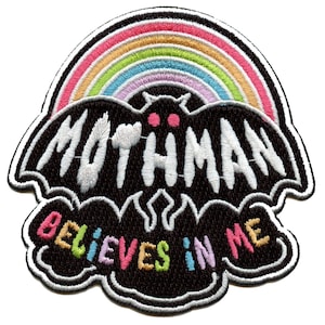 Op de afbeelding: Geborduurde patch met een zwart Mothman-silhouet en het woord "MOTHMAN" in het wit. Een regenboogboog staat boven de mot, en de zin "BELIEVES IN ME" staat eronder in kleurrijke letters. De patch heeft een witte rand.