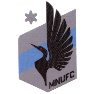 May include: A gray and blue patch with a black bird design and the text "MNUFC". A small gray star is in the upper left corner.