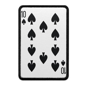 Può includere: Toppa rettangolare raffigurante il dieci di picche. La carta ha uno sfondo bianco con dieci simboli di picche neri e il numero 10 agli angoli. La toppa è bordata da un bordo nero cucito.