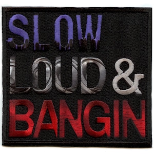 Könnte beinhalten: Schwarzer gestickter Aufnäher mit dem Text "SLOW LOUD & BANGIN" in lila, silbernen und roten Buchstaben.