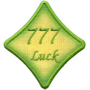 Könnte beinhalten: Ein grüner, rautenförmiger Patch mit gelber Mitte. Der Patch ist mit der Zahl 777 und dem Wort "Luck" bestickt.