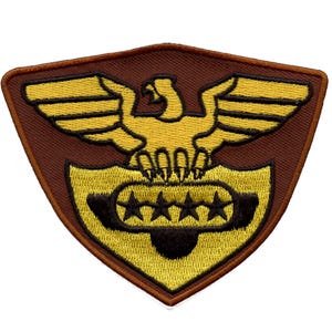 May include: Embroidered patch featuring a golden eagle with outstretched wings above a shield with four stars. The patch has a brown border and background, with a yellow and black design.