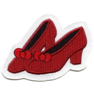 May include: A pair of red embroidered shoes with black heels and red pom-poms on the toes.